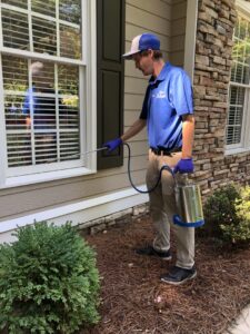 A Capital Pest Services technician spraying the foundation of a house for pest control in Raleigh, NC.