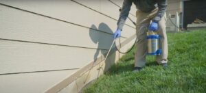 A pest control technician spraying the foundation of a house for pest prevention at Richmond Pest Control in Richmond, KY.
