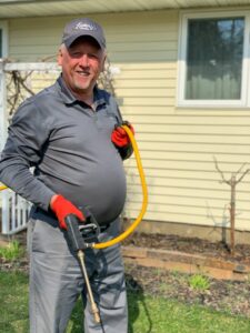 A pest control technician from Larry's Pest Control, Inc spraying the exterior of a house in Lake Worth, FL.