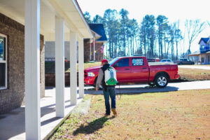 A pest control technician from Liberty Pest Services LLC spraying the perimeter of a house in Mayflower, AR.