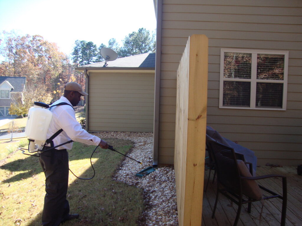A pest control technician from Nature Is My Office LLC spraying the perimeter of a house in Cincinnati, OH.