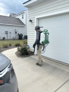 A pest control technician from Port City Pest Control wearing a backpack sprayer, treating a residential property in Summerville, SC.