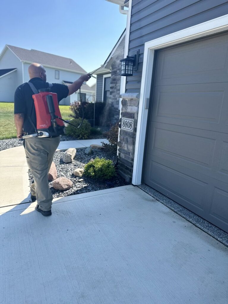 A Ramer Pest Control technician spraying the exterior of a house for pest control in Fort Wayne, IN.