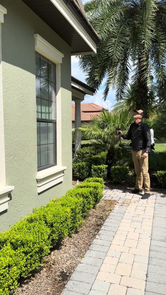A Sorko Services technician performing pest control treatment around the foundation of a house in Sanford, FL.