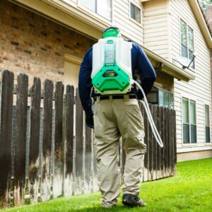 A pest control technician from Harvey's Pest Control spraying a residential lawn in Los Angeles, CA.