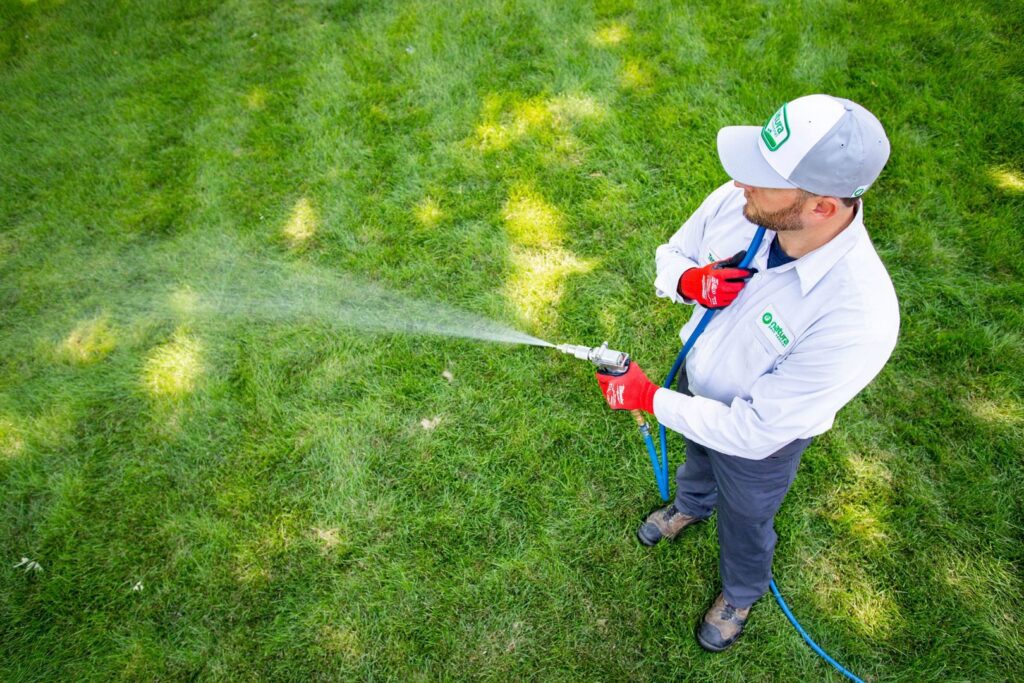 A Natura Pest Control technician spraying a residential lawn as part of a pest control service in Boise, ID.