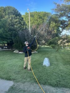 An Elite Pest Control technician spraying outdoor foliage for pest treatment in Maple Grove, MN.