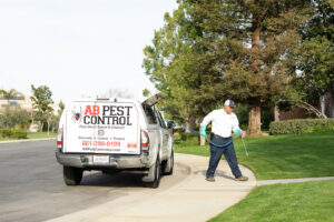 A pest control technician from AB Pest Control spraying the perimeter of a residential property in Bakersfield, CA.