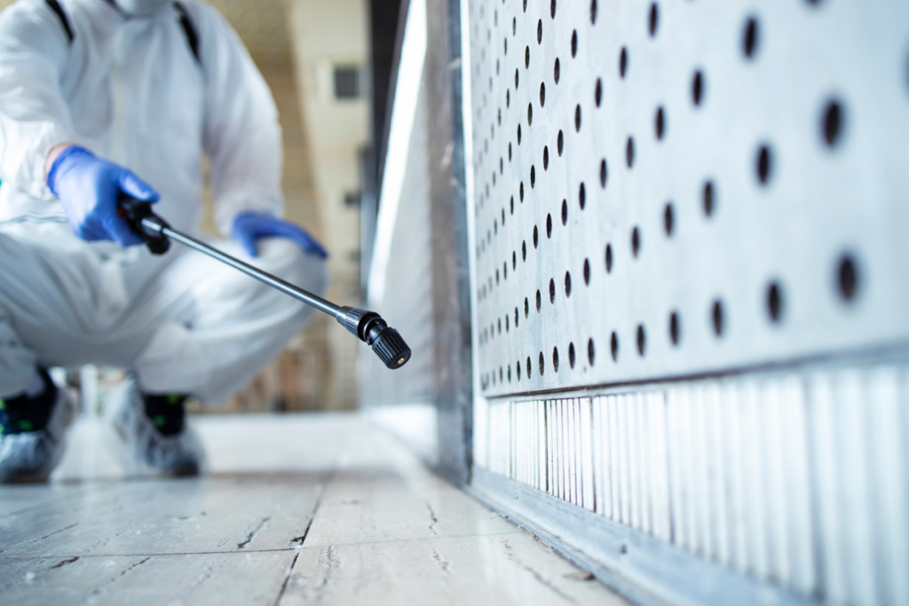 A pest control technician in a hazmat suit spraying for pests at a property in Tulsa, OK, by Pest Patrol.