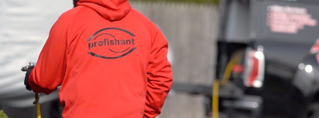 A pest control technician wearing a Profishant hoodie and spraying a treatment for Profishant, inc. in New Bedford, MA.