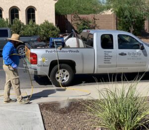 A pest control technician spraying a yard from a service truck at Bye Bye Bugs Pest Control in Indianapolis, IN