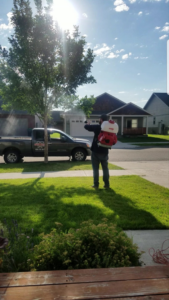 A pest control technician from Southwest Bug & Pest spraying a residential yard in Bozeman, MT.