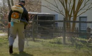A pest control technician spraying a residential yard with a backpack sprayer for Richmond Pest Control in Richmond, KY.