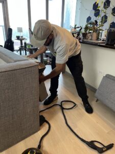 A Sleep Tight Pest Control technician using a steamer to treat a sofa in a Kansas City, KS residence.