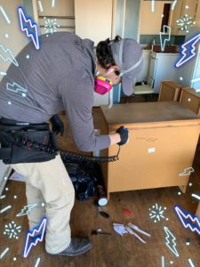 A pest control technician treating an area near a cabinet during a service by RoadRunner Pest Management in Albuquerque, NM.