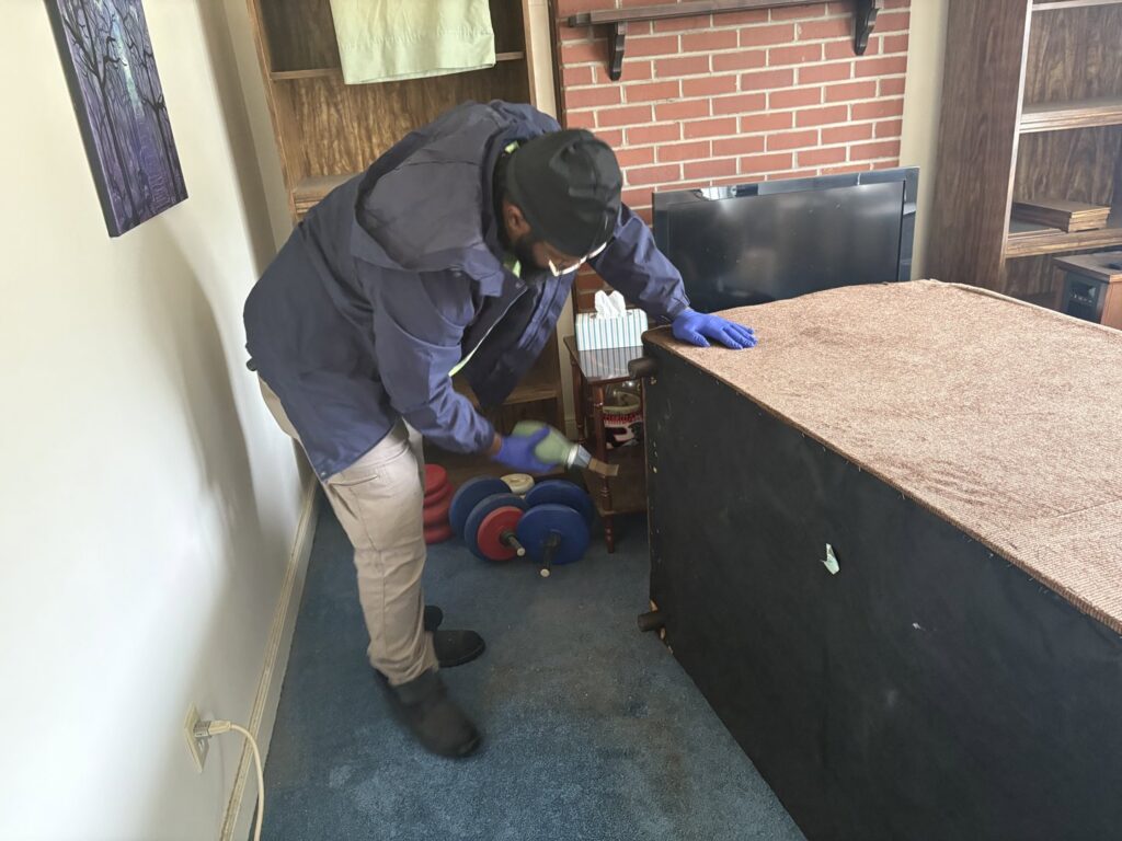 A SanPro Pest Control VA technician applying treatment to the underside of furniture in Richmond, VA.
