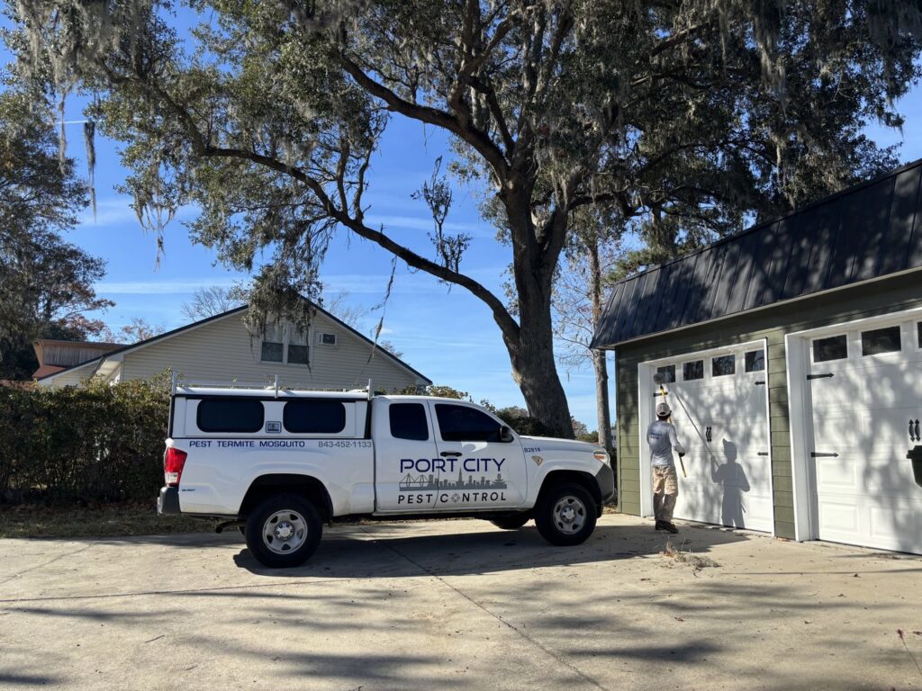 A Port City Pest Control technician applying pest treatment to the exterior of a garage door in Summerville, SC.