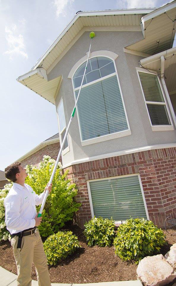 A pest control technician from EDGE - The Service Company treating the eaves of a house in Bridgeview, IL.