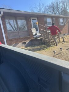 A pest control technician treating the exterior of a house with a long pole for pest management by DOA Pest Service in Nashville, TN.
