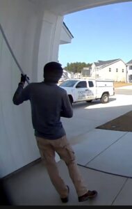 A Port City Pest Control technician treating the exterior of a house with a long pole in Summerville, SC.