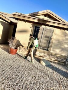 A CAPE Pest Control technician treating the foundation of a residential home for pests in Mesa, AZ