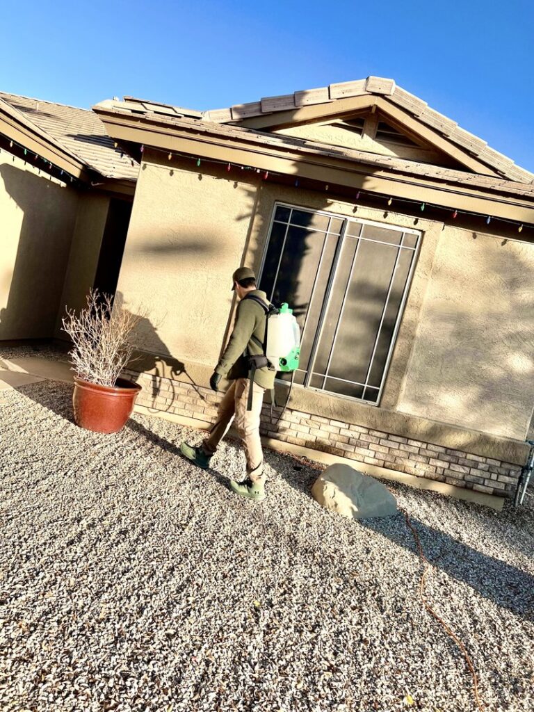 A CAPE Pest Control technician treating the foundation of a residential home for pests in Mesa, AZ