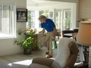 A pest control technician applying treatment to indoor plants with a handheld sprayer by EcoPro Termite & Pest in Dayton, OH