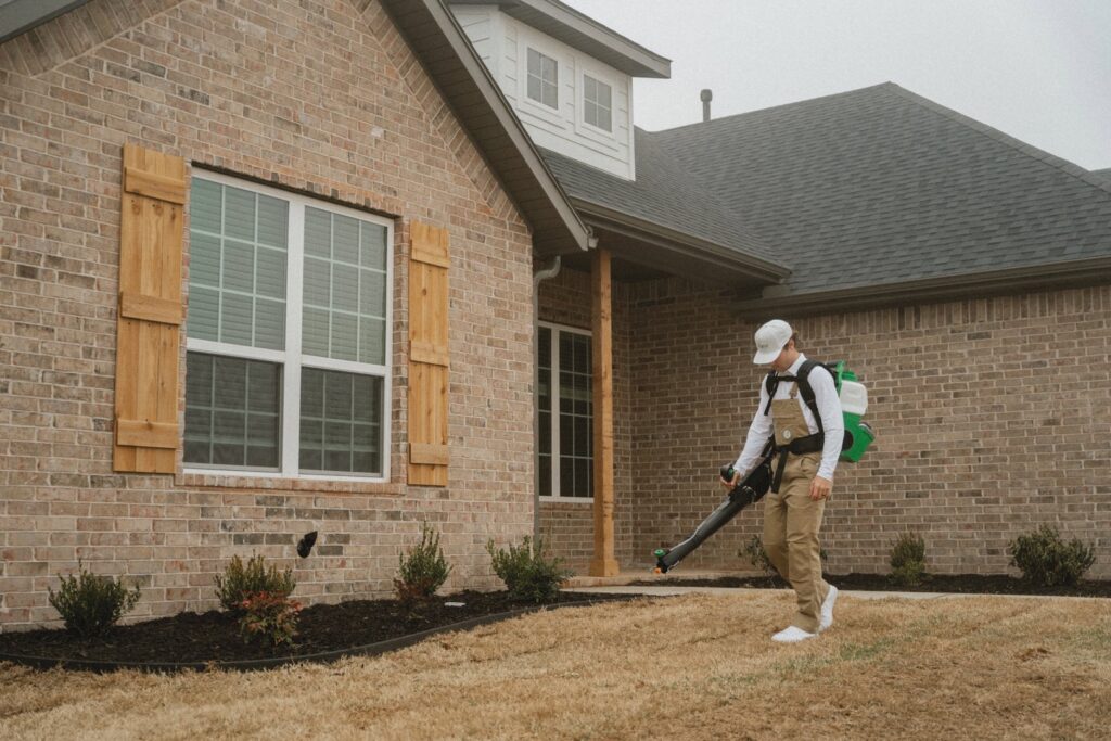 A Breezy Pest Control technician treating a lawn with a pest control device in Little Rock, AR.