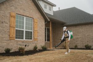 A Breezy Pest Control technician treating a lawn with a pest control device in Little Rock, AR.