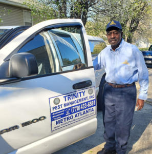 A Trinity Pest Management, Inc. technician standing next to a company truck in Redan, GA, ready for a pest control job.