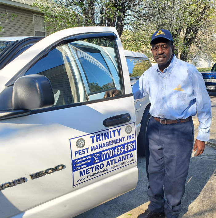 A Trinity Pest Management, Inc. technician standing next to a company truck in Redan, GA, ready for a pest control job.