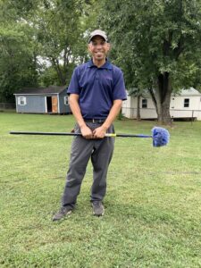 A pest control technician holding a cobweb duster, ready for service, for Ameri Care Services, Inc. in Murfreesboro, TN.