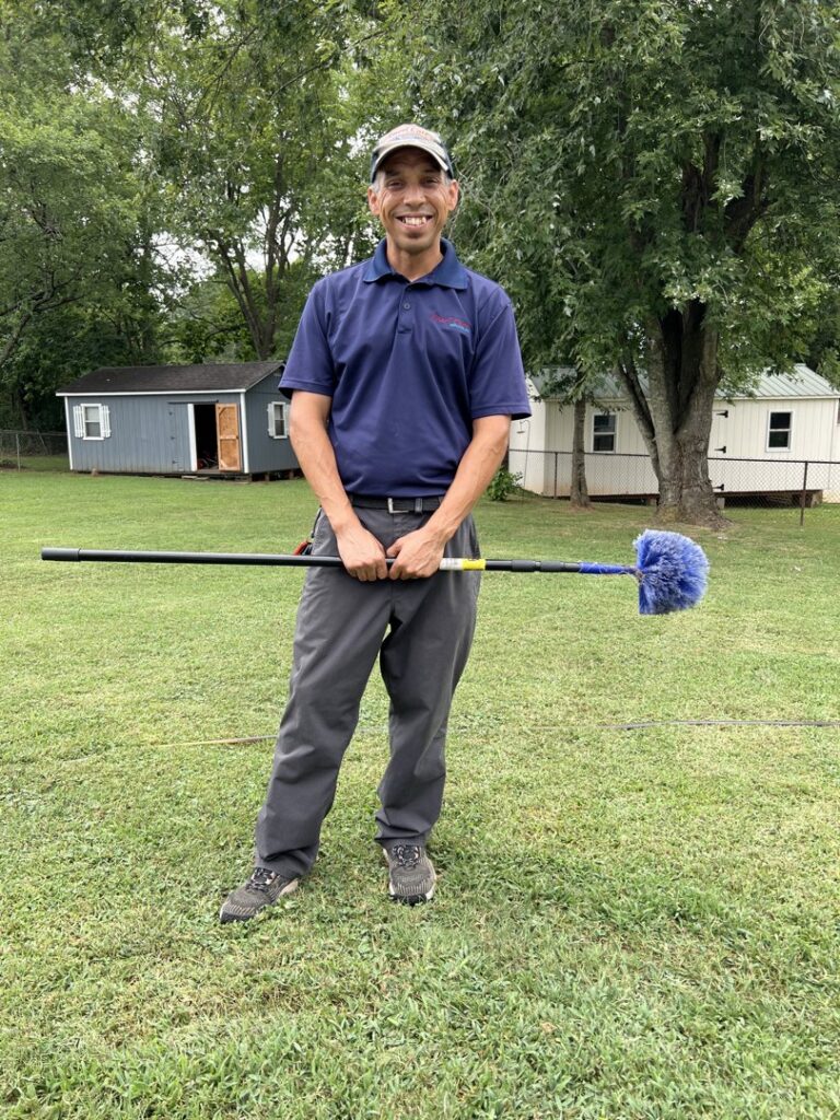 A pest control technician holding a cobweb duster, ready for service, for Ameri Care Services, Inc. in Murfreesboro, TN.
