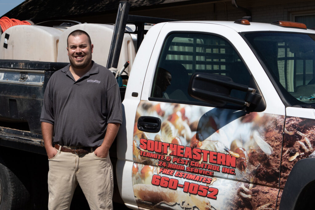 A pest control technician standing with a company truck and equipment at Southeastern Termite & Pest Control in Lake Worth, FL