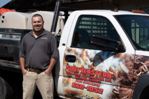 A pest control technician standing with a company truck and equipment at Southeastern Termite & Pest Control in Lake Worth, FL