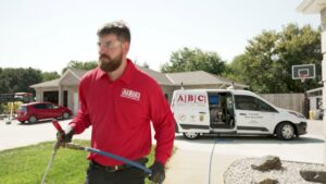 A pest control technician from ABC Termite & Pest Control, Inc holding a sprayer with a branded van in Lincoln, NE.