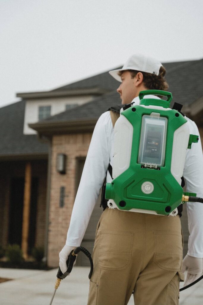 A Breezy Pest Control technician with a backpack sprayer approaching a home for service in Little Rock, AR.
