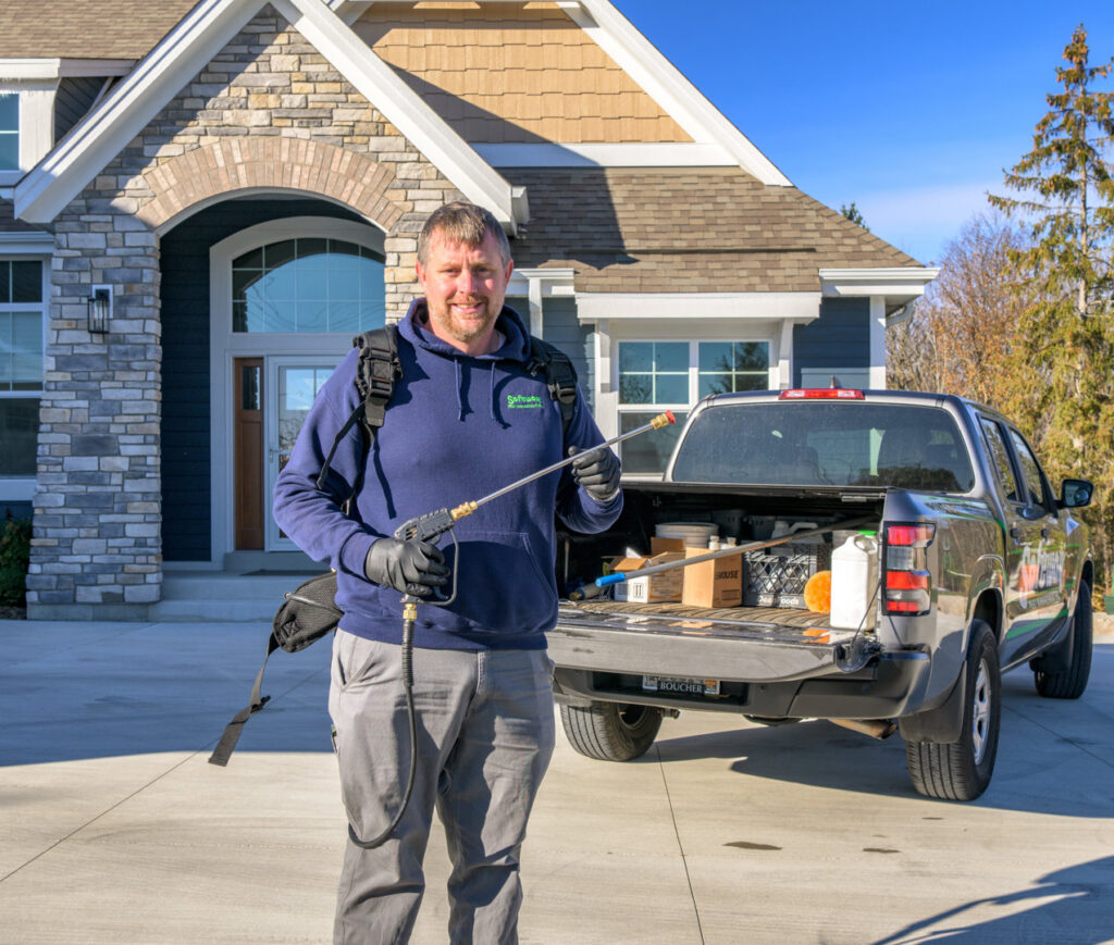 A Safeway Pest Management technician with a backpack sprayer and wand ready for service at a residential home in Muskego, WI.