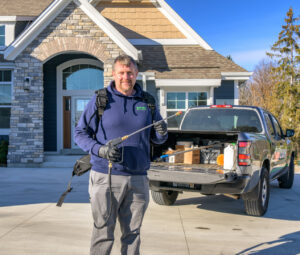 A Safeway Pest Management technician with a backpack sprayer and wand ready for service at a residential home in Muskego, WI.