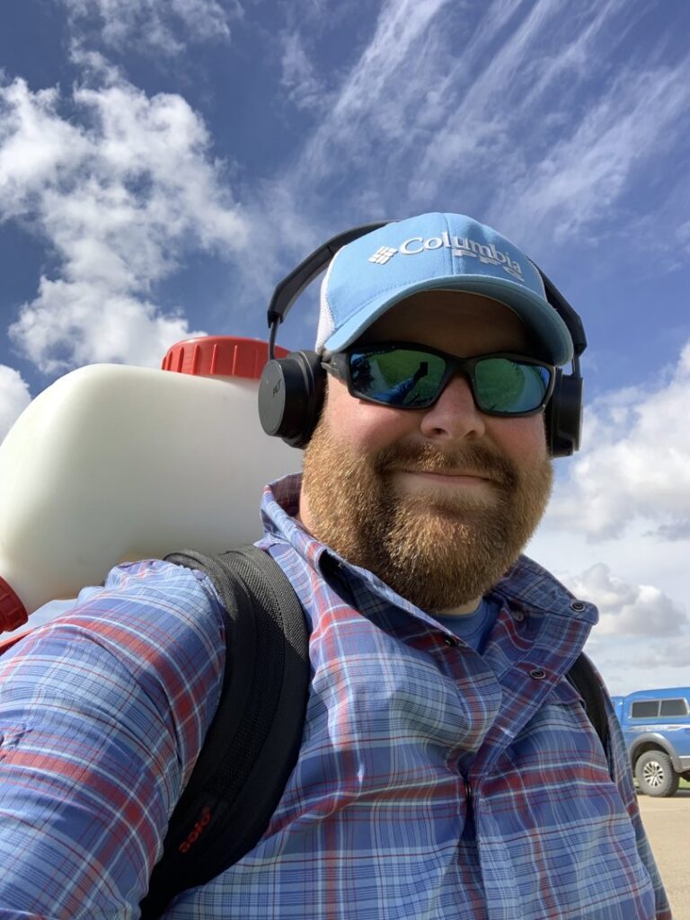A Patriot Mosquito technician in Minot, ND, wearing a backpack sprayer and headphones, ready to perform pest control services.