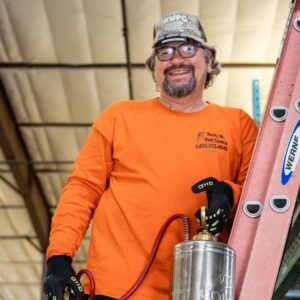 A pest control technician from Rocky Mountain Pest Control in Santa Fe, NM, holding a sprayer and standing next to a ladder, ready for service.