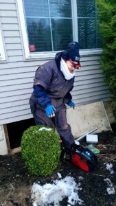 A Mario's Pest Control technician in protective gear working near a crawl space entrance for pest control in Hamilton, NJ.