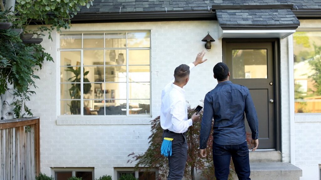 Hawx Pest Control technicians inspecting a house exterior and discussing treatment options in San Antonio, TX.