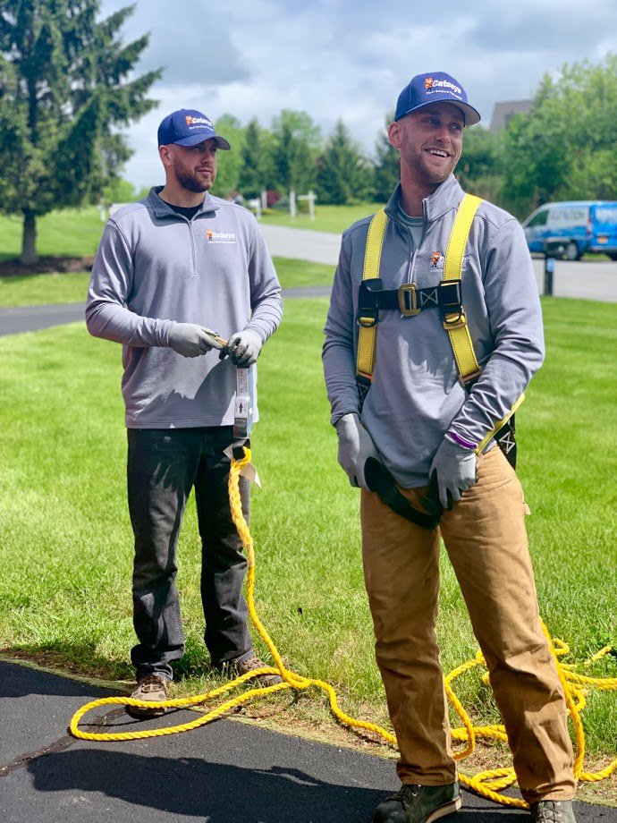 Two Catseye Pest Control technicians on a residential job site, one wearing a safety harness, in Hartford, CT.