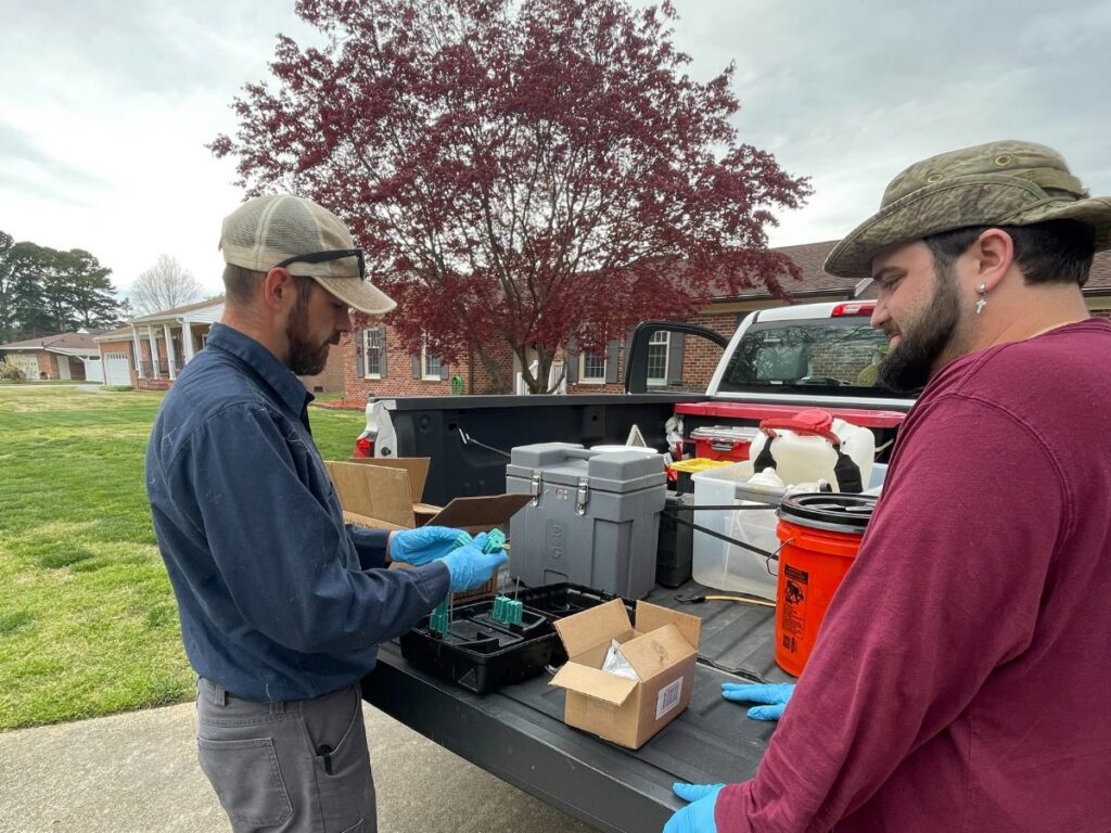 Pest control technicians preparing equipment from a truck for a job at Colonial Exterminating Co Inc in Newport News, VA