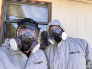 Two pest control technicians in full protective suits and respirators from Absolute Pest Solutions in Piedmont, OK.