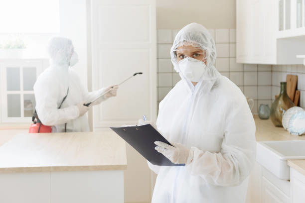 Pest control technicians in protective suits spraying in a kitchen for Complete Exterminating INC in Vancouver, WA.