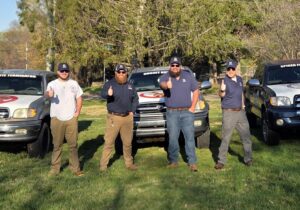 Four pest control technicians from Pest In Class Exterminating standing proudly with their branded service trucks in Johnson City, TN.