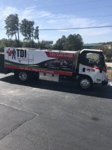 Small pest control treatment devices visible in a residential yard maintained by TDI Lawn & Pest - Birmingham, AL.