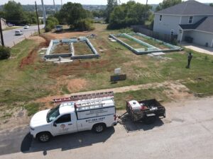 An aerial view of a D' Bug Man Pest Control truck and trailer at a construction site in Arlington, TX.